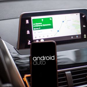 Driver using Android Auto in a car, showcasing seamless connectivity and access to music, navigation, and updates while keeping hands on the wheel.
